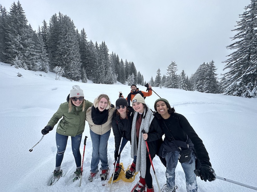 A group of people in snowshoes on a mountain smiling.