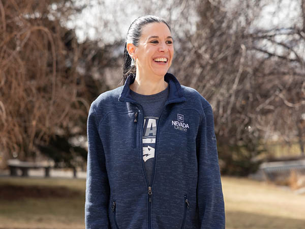 Carley Ries stands outside near Manzanita Lake, looking into the distance, smiling.