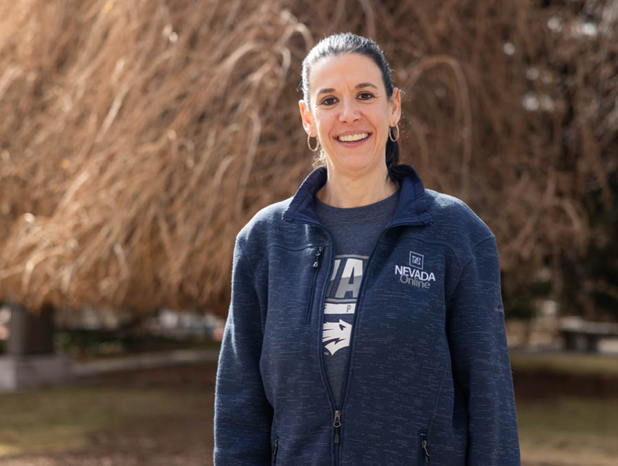 Carley Ries smiles at the camera, standing outside near Manzanita Lake in the winter