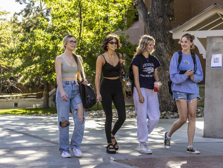 A group of four students walk along a path on the Quad.