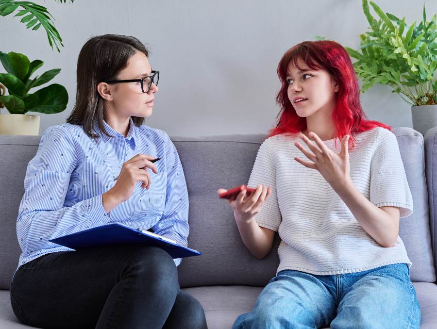 An adult and a teen sitting on the couch talking