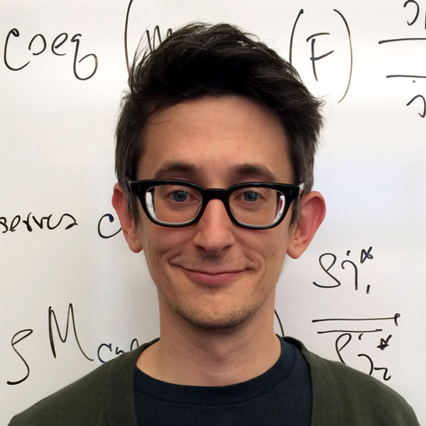 Portrait of Chris Rogers with a whiteboard behind him covered in math symbols.