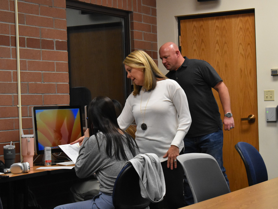 Kim and John providing feedback to a student working on classwork. 