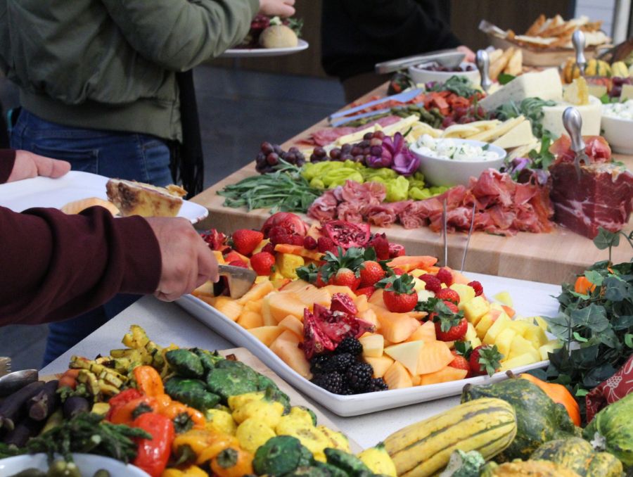 Students serving themselves fruits, cheeses, meats, and vegetables.