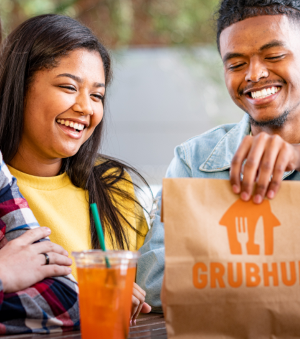 Two students smiling with a bag from Grubhub