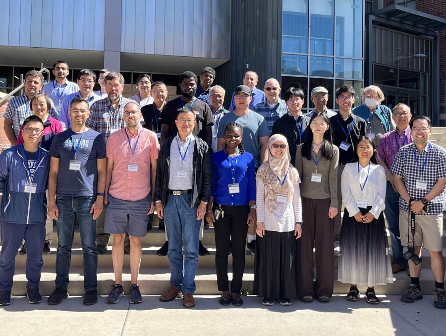 A group of people smile for a photo outside the Davidson Mathematics and Science Center.
