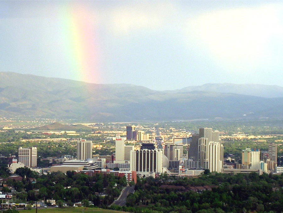 A rainbow descends from the top left part of the photo toward downtown Reno.