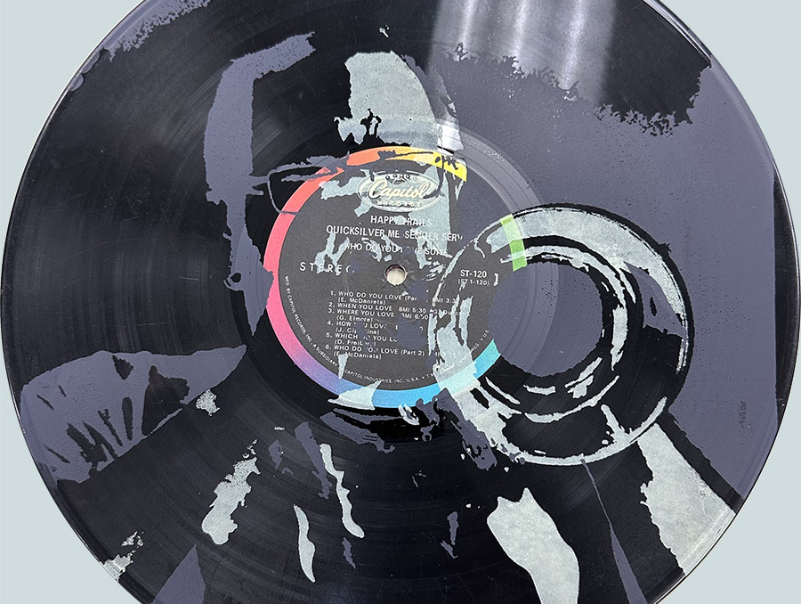 The sticker design incorporates a high-contrast image of the artist playing a trumpet silk-screened in gray and white over a photograph of a vinyl LP record.