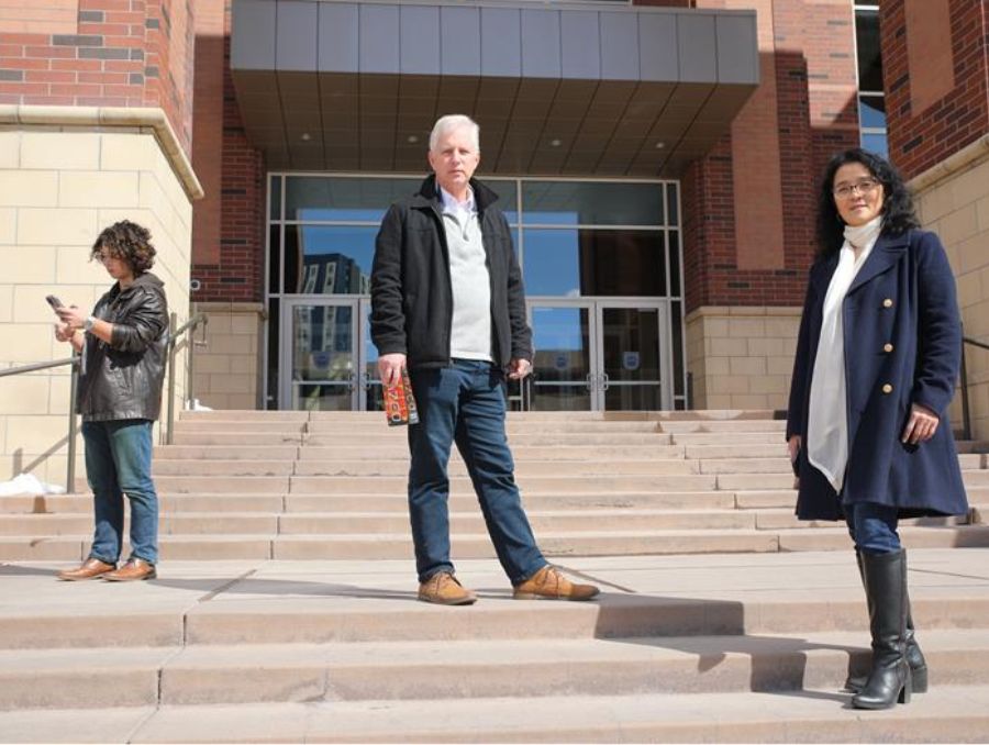 Two professors and a student holding a phone