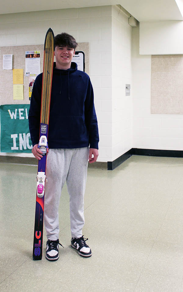 Teenager standing in hallway with a single ski