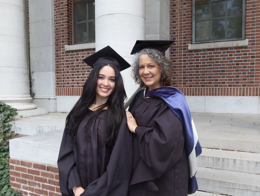 Debi (right) and Kaylie (left) posing in their graduation cap and gowns on campus.