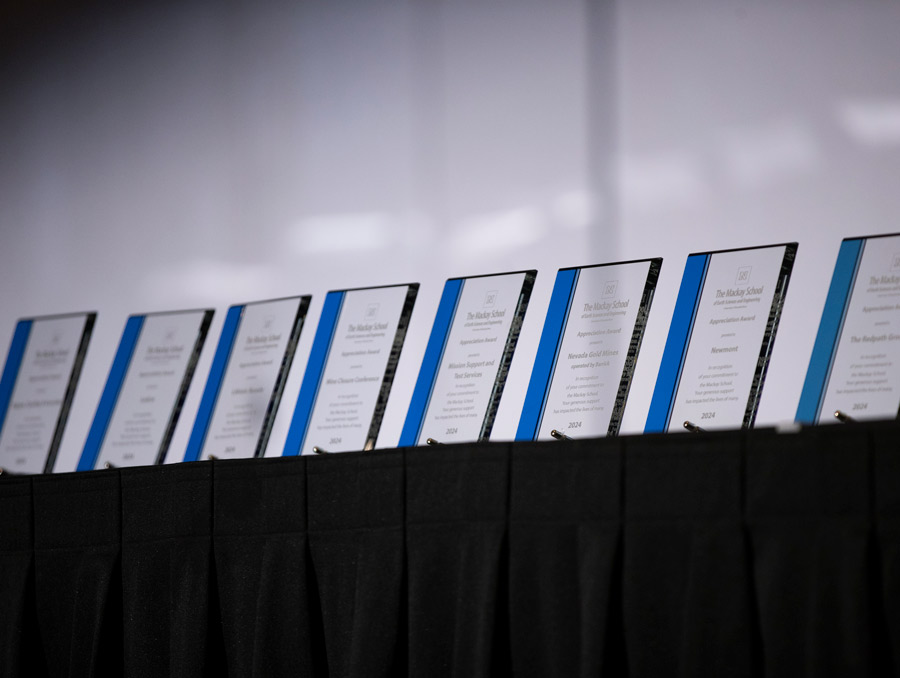 Glass awards with inscriptions lined up on a table.