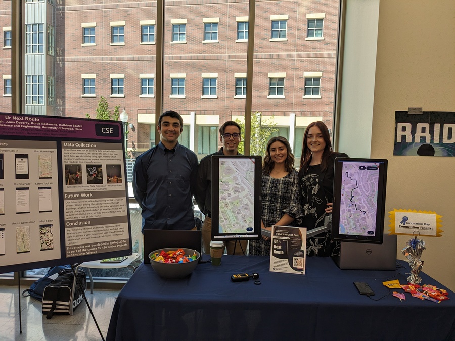 Four students stand behind a desk at Innovation Day where they presented their safety app.