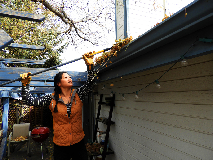 Woman cleaning a gutter.