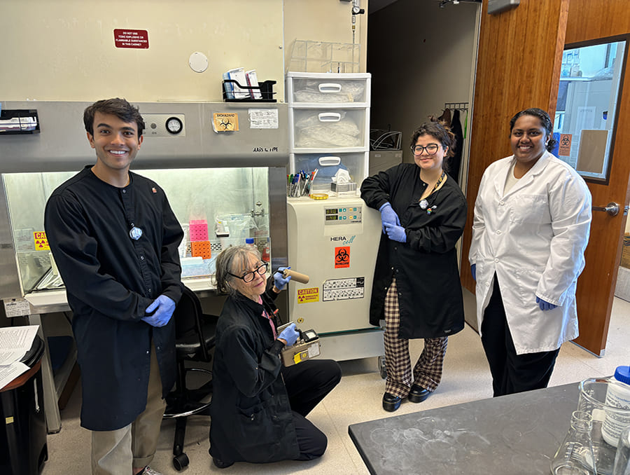Dr. Hudig and students posing near safety equipment in a lab.