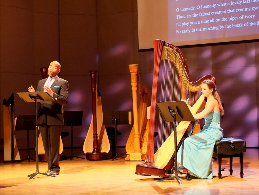 A man singing and a woman playing the harp.