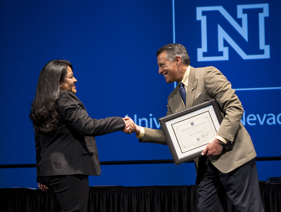 An awardee shakes hands with President Sandoval onstage during Honor the Best.