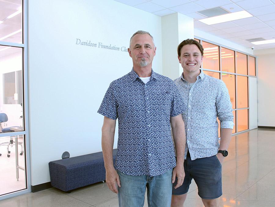 Jay and Nathan Thom standing in front of the Cleanroom in the William Pennington Engineering Building