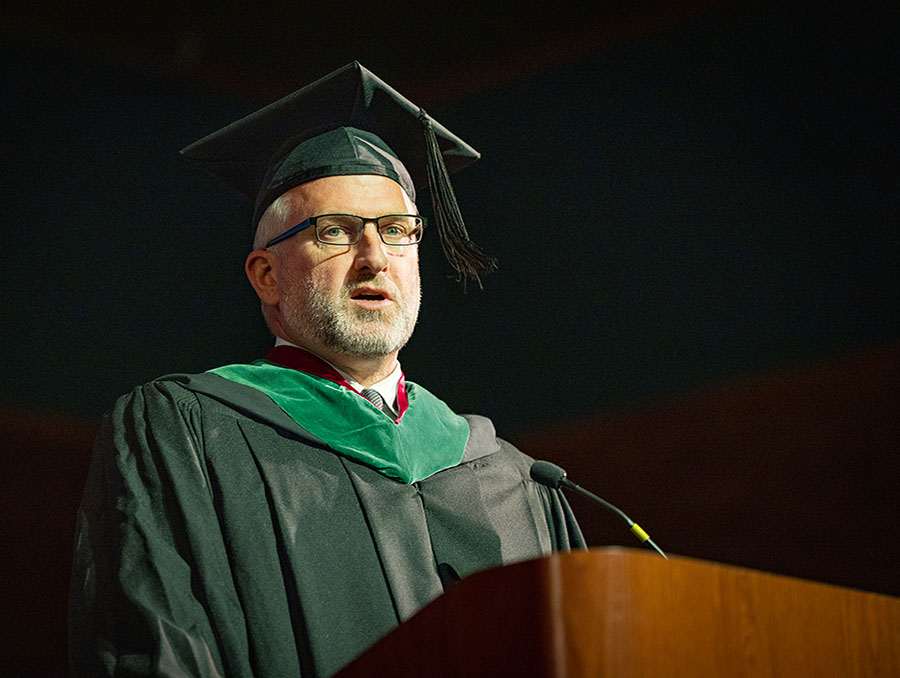 Keynote speaker Daniel Coll addressing the Class of 2025 on stage.