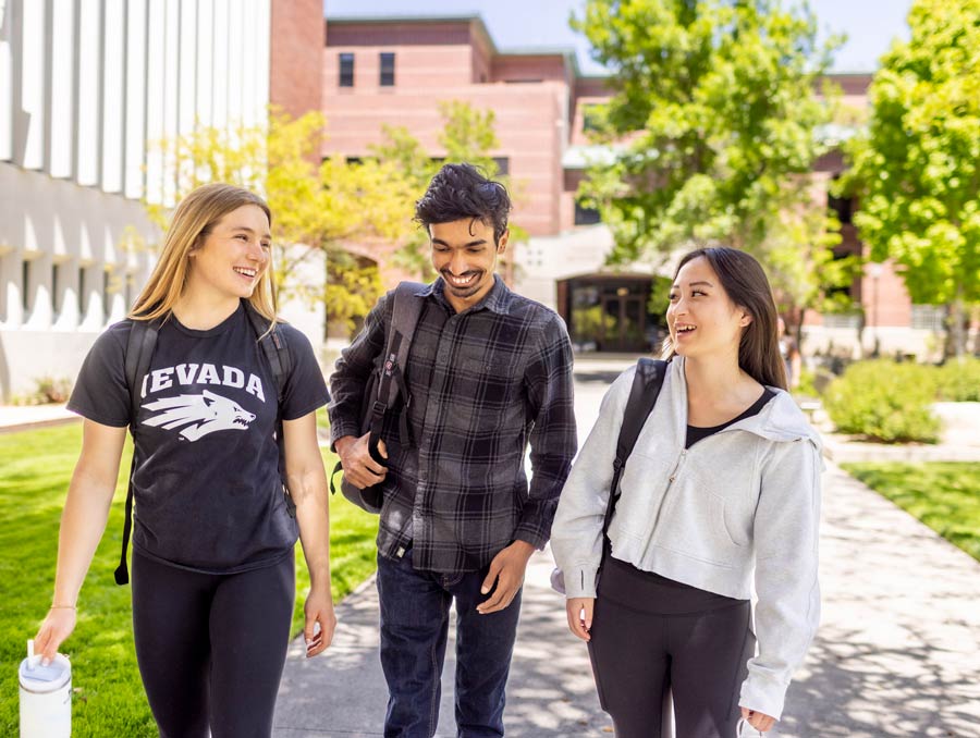 Three students walk on campus next to the Effie Mona Mack building.