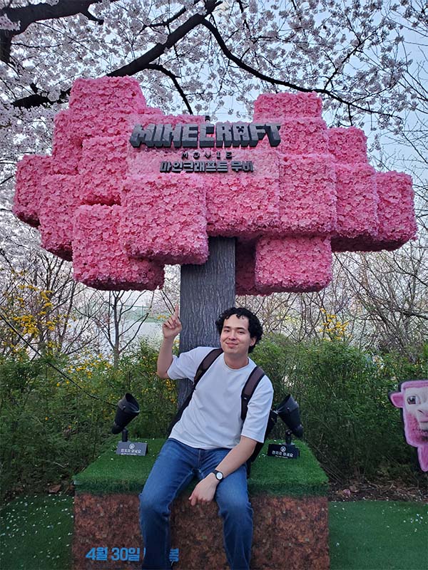 Man standing outdoors underneath a promotional movie sign.