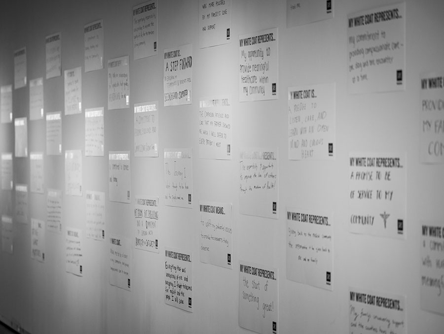 Wall with posters that the M.D. Class of 2029 wrote with what their white coat represents to them.