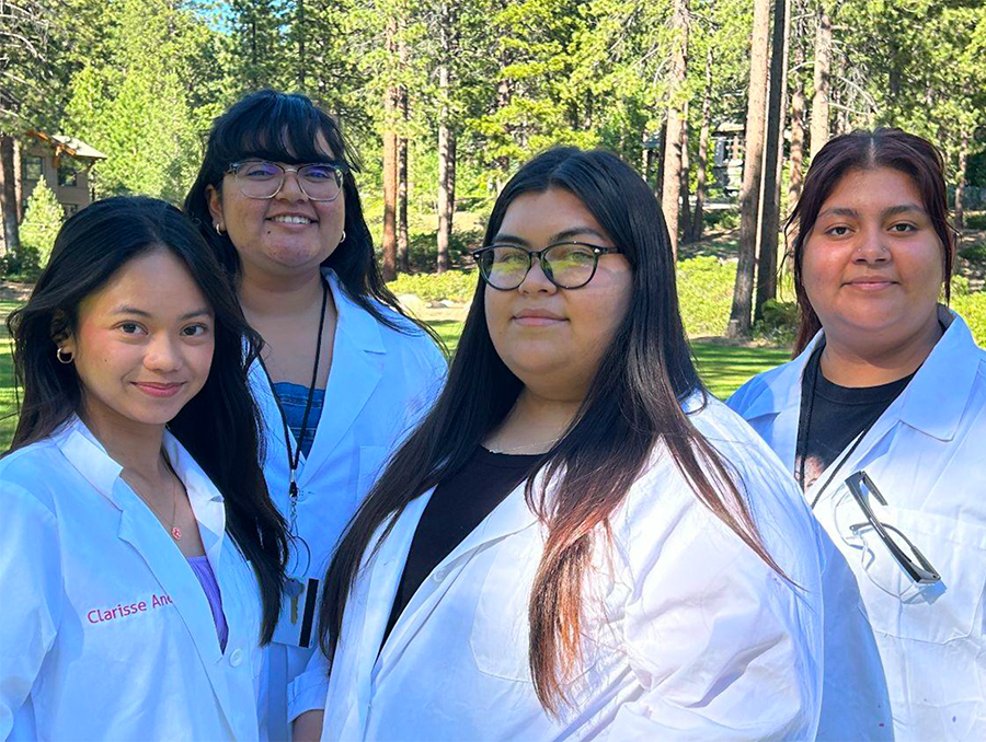 Four Women wearing lab coats and posing for a picture outside