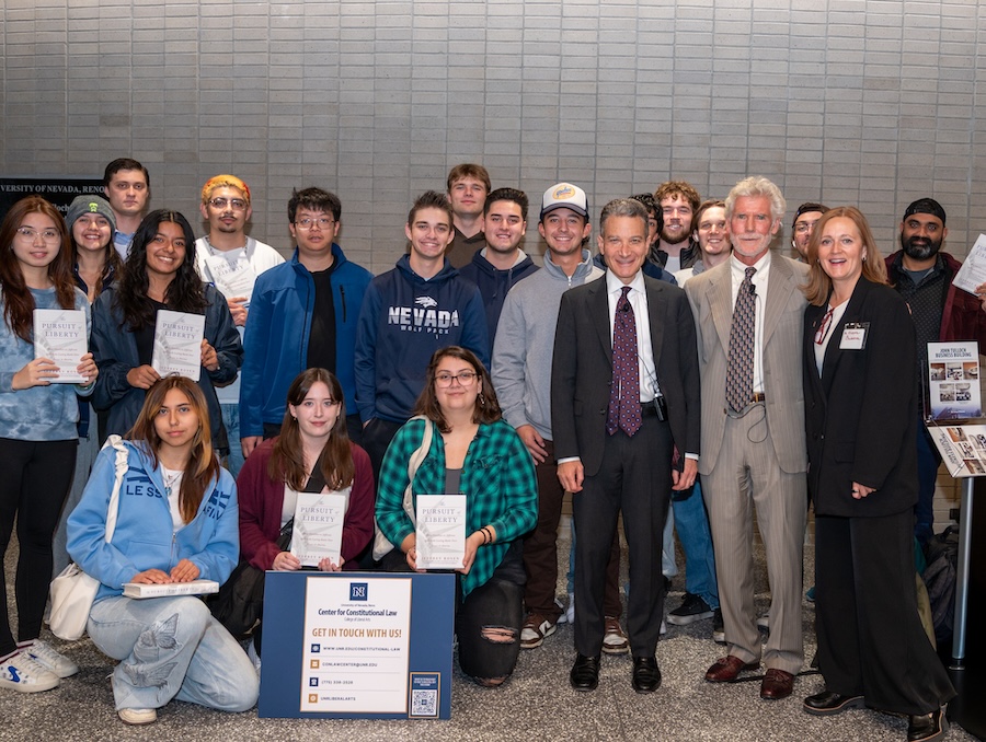 A large group of student stand near Rosen and Trahock. Some student hold the "Pursuit of Liberty" book.