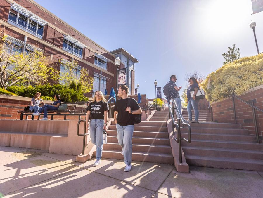 Students chat while walking down a set of steps on campus.