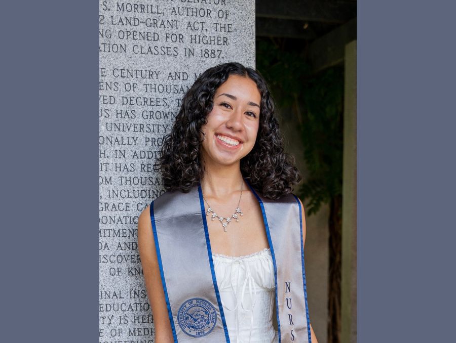 Maysun smiling outside, wearing a graduation sash.