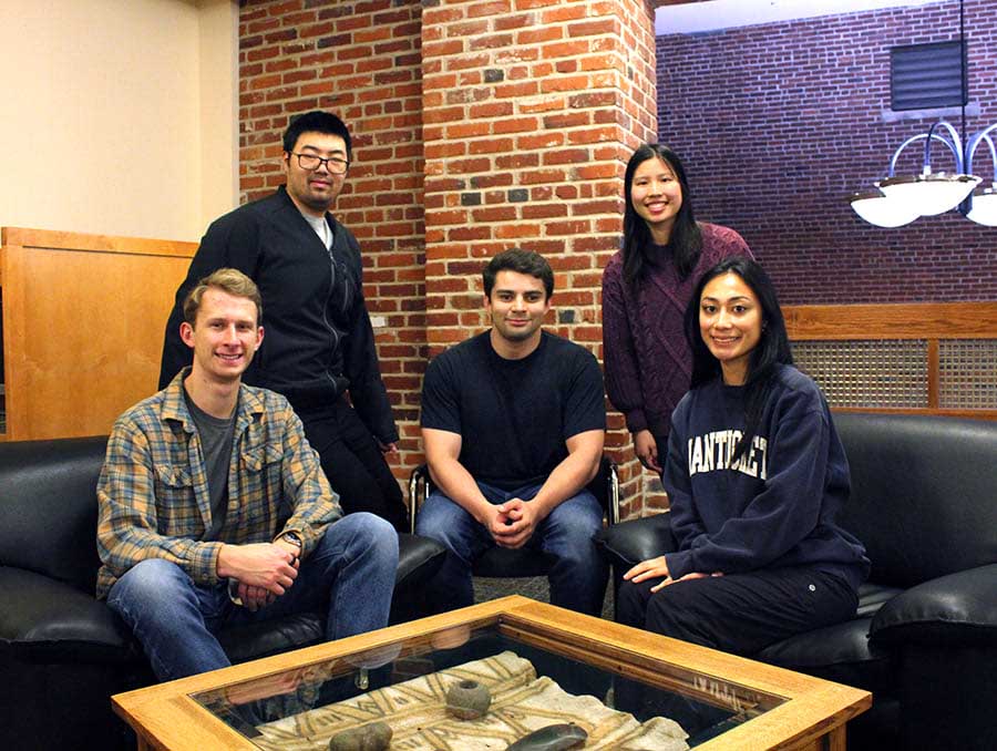 Five people, three seated and two standing, pose in a library setting.
