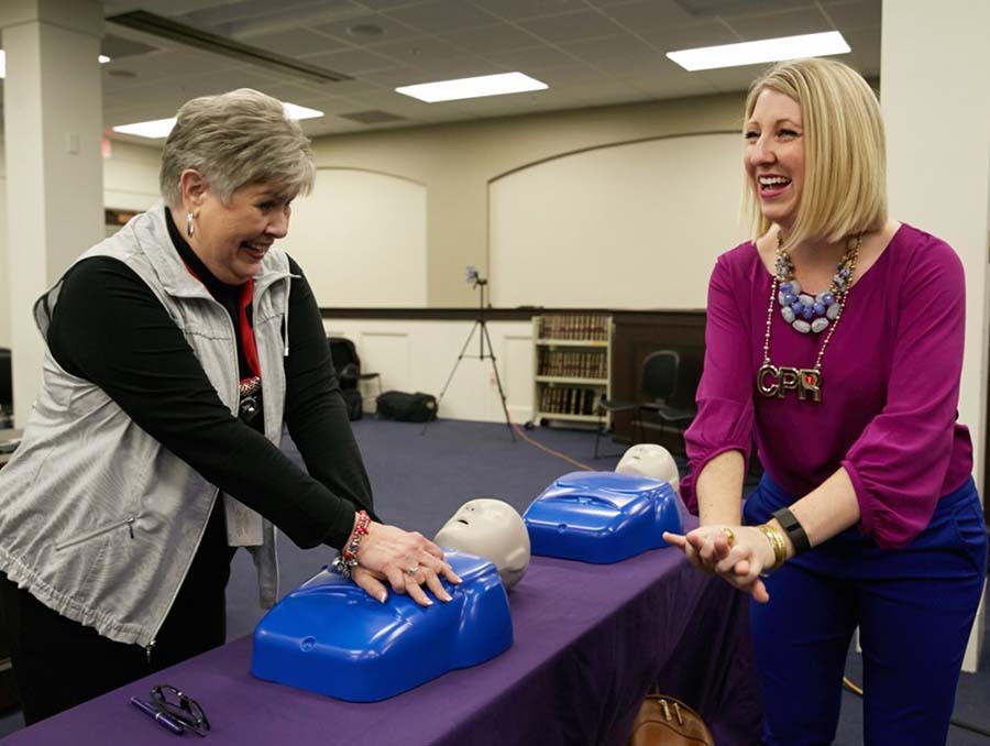 Professor of cardiology, Lorrel Toft, M.D., training a woman on CPR techniques.