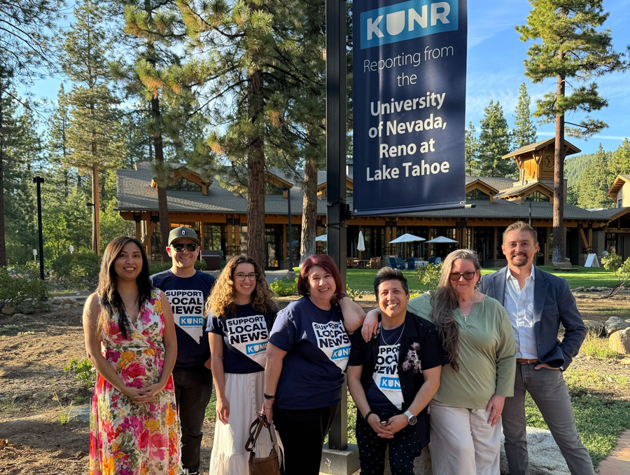 KUNR staff wearing branded shirts that read "support local news" at the University of Nevada, Lake Tahoe campus under a banner that reads "KUNR reporting from the University of Nevada, Reno at Lake Tahoe."