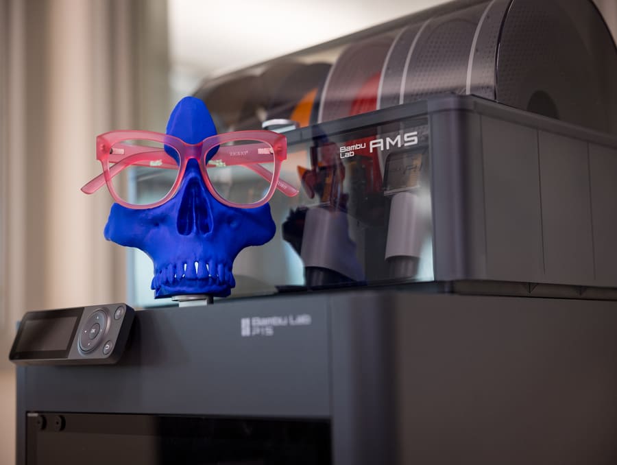 Two 3D printers, one filament-based for durable prints and one resin-based for detailed models, side by side on a workstation in The Lab@Savitt.