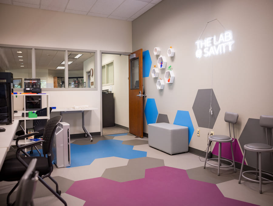 A modern, open tech suite inside the Savitt Medical Library featuring 3D printers, VR headsets, workstations, and study pods designed for hands-on, interdisciplinary learning.