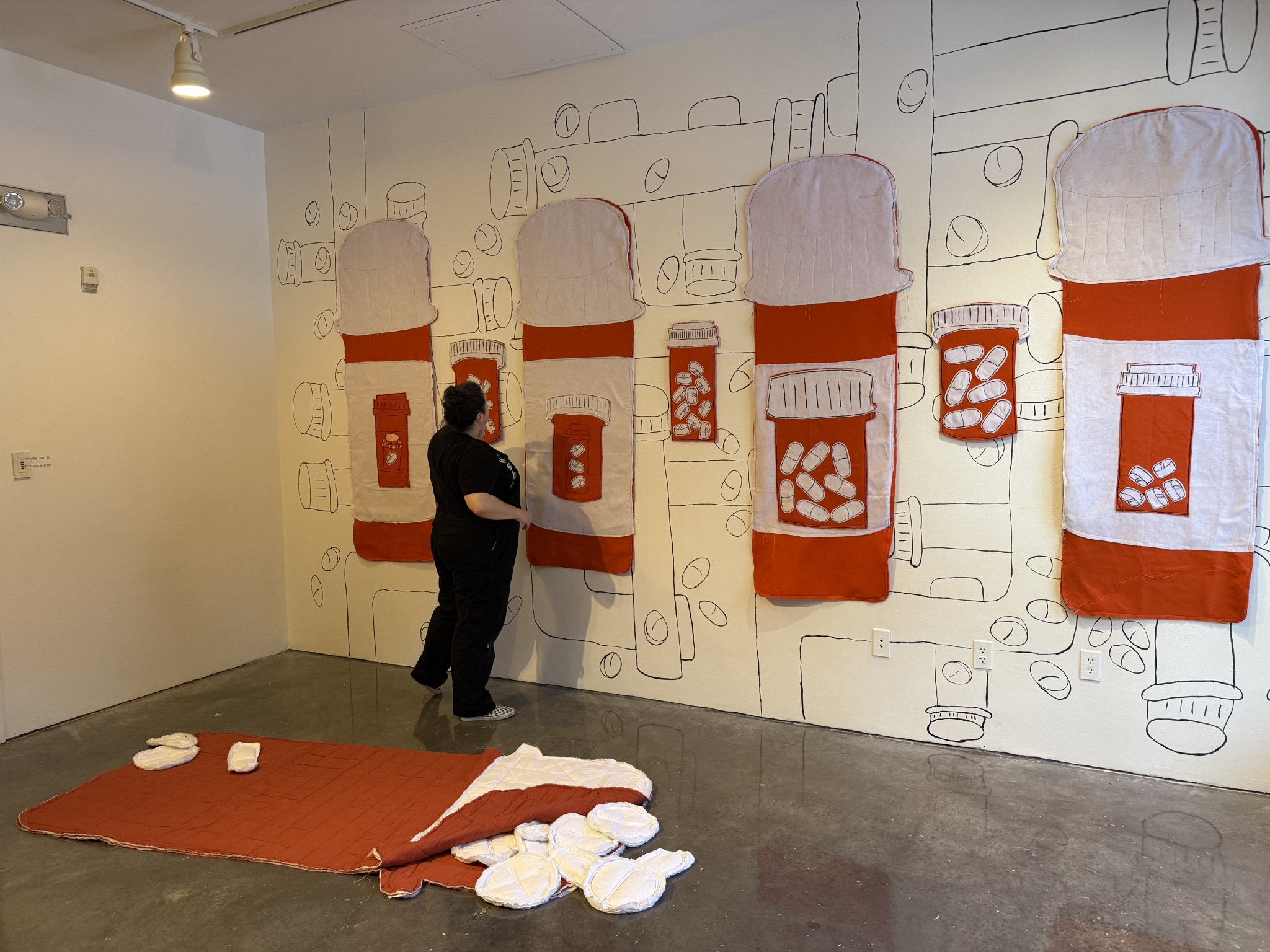 Person looking at an art wall that showcases large pill bottles. 
