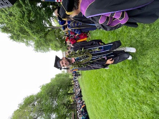 Salois on the university's quad during commencement, wearing a cap and gown and lei.