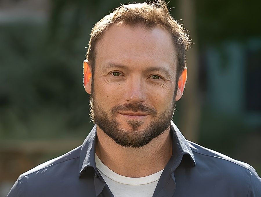 A headshot of a smiling man.
