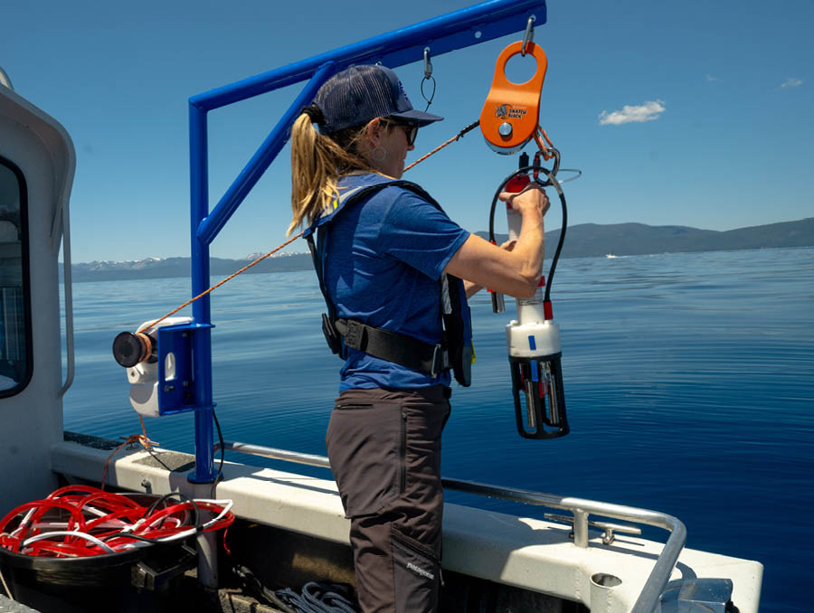 Carina Seitz lowers lab equipment into the water off the side of the boat.