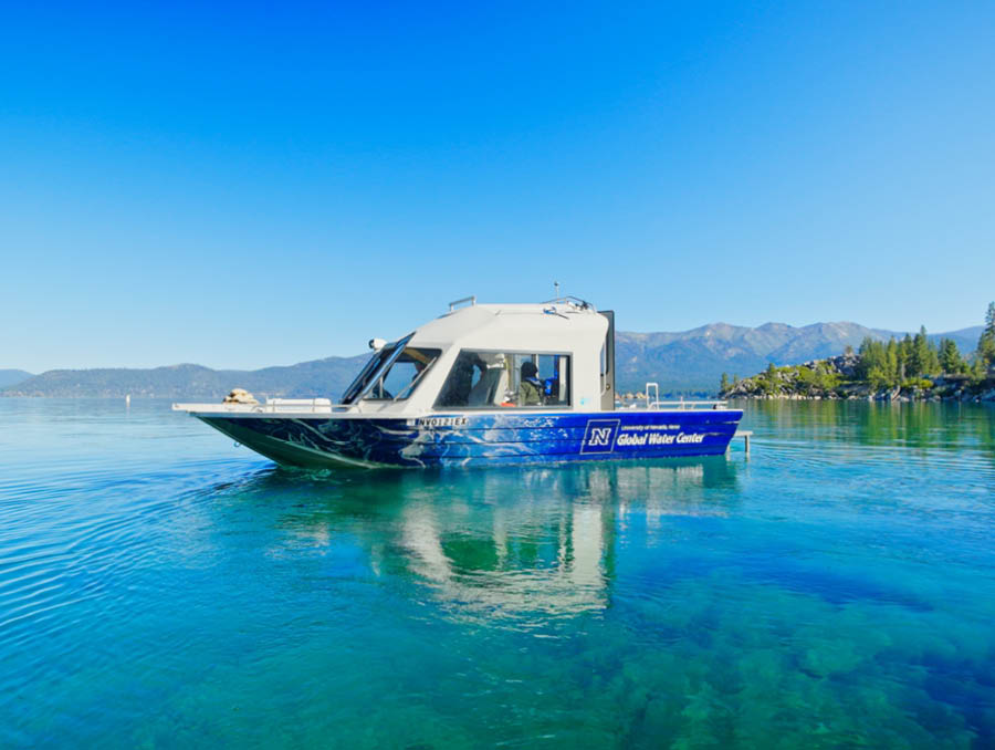 A research boat floats on Lake Tahoe with blue water and skies.