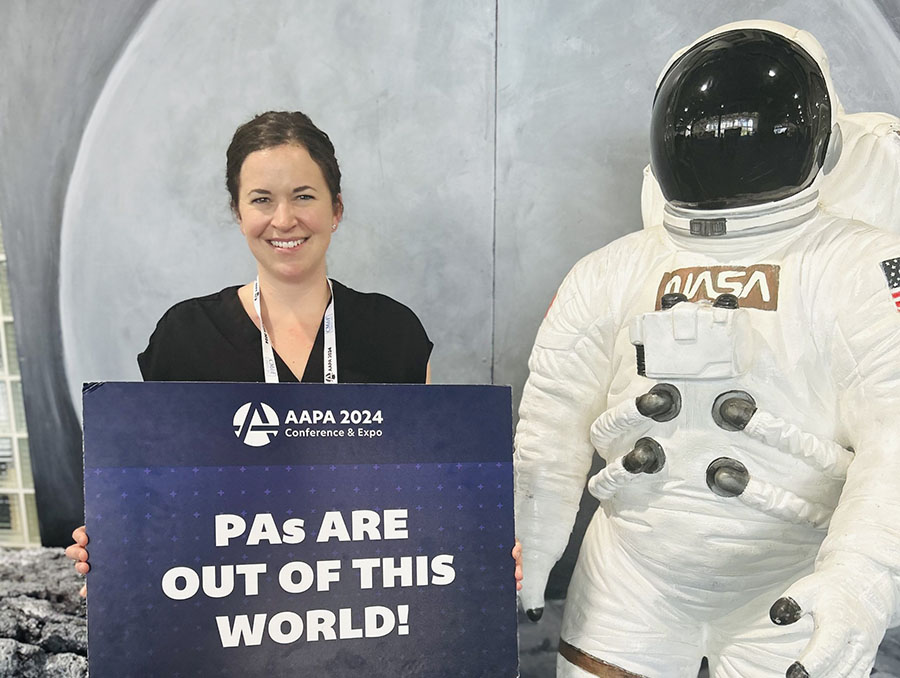 Tiffany Scheller holding a sign next to an astronaut statue that says "PAs are out of this world."
