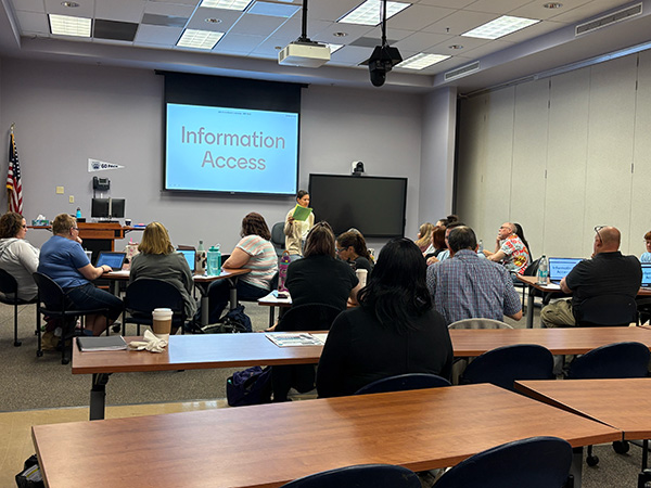 Person standing at the front of a conference room teaching a lesson to a group of people.