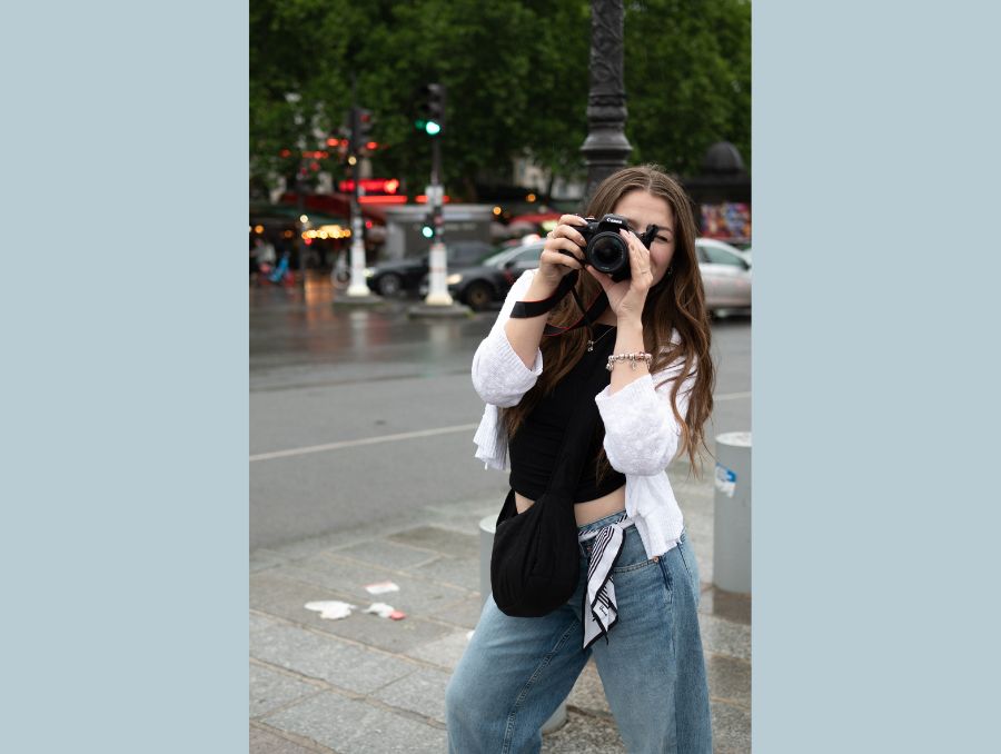 Makayla taking a picture with a camera of the street.