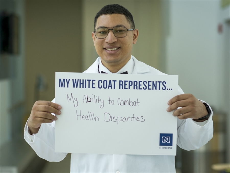 Portrait of M.D/Ph.D. student, Steven Christian, holding a sign that reads "My white coat represents ... my ability to combat health disparities."