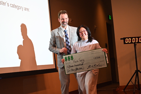 A woman smiling while holding a big check.