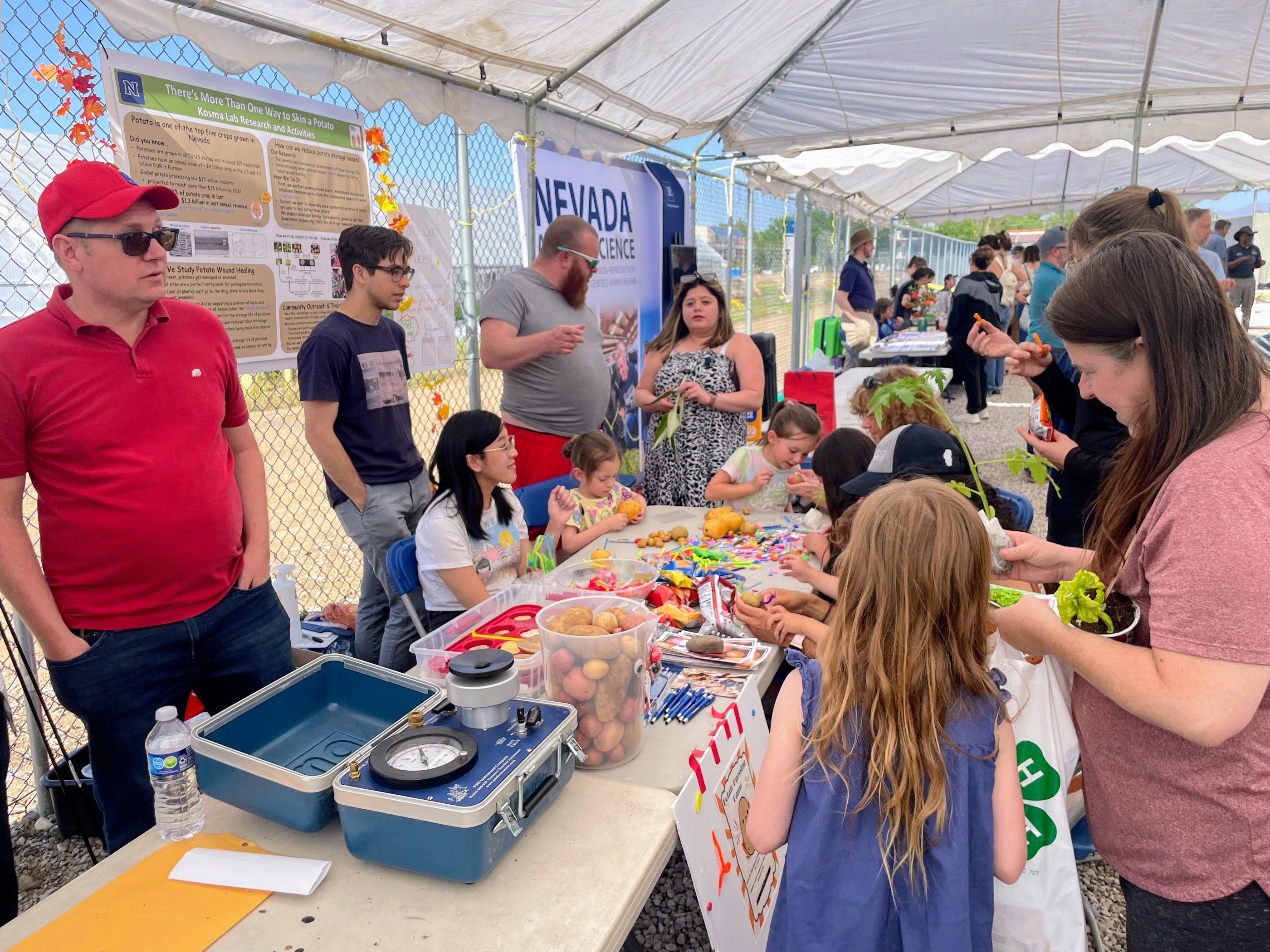 Men, women and children standing around a table with craft material.