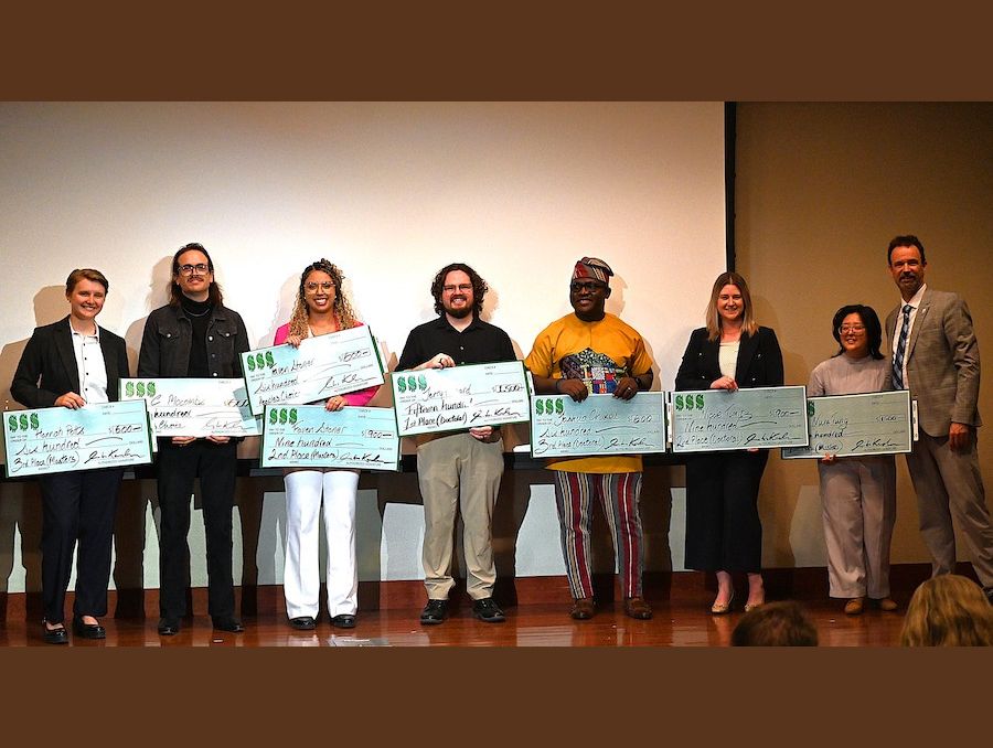 A group of people standing on stage holding giant checks.