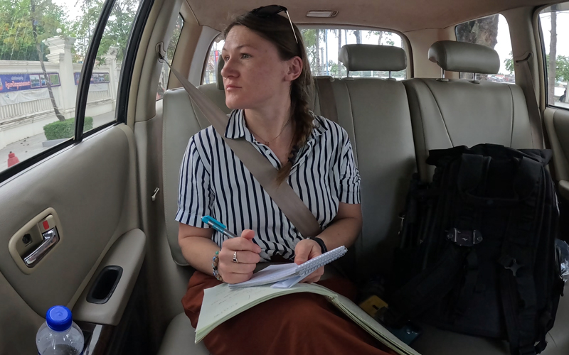 Kat Fulwider sits in the back of a taxi while taking notes on her observations.