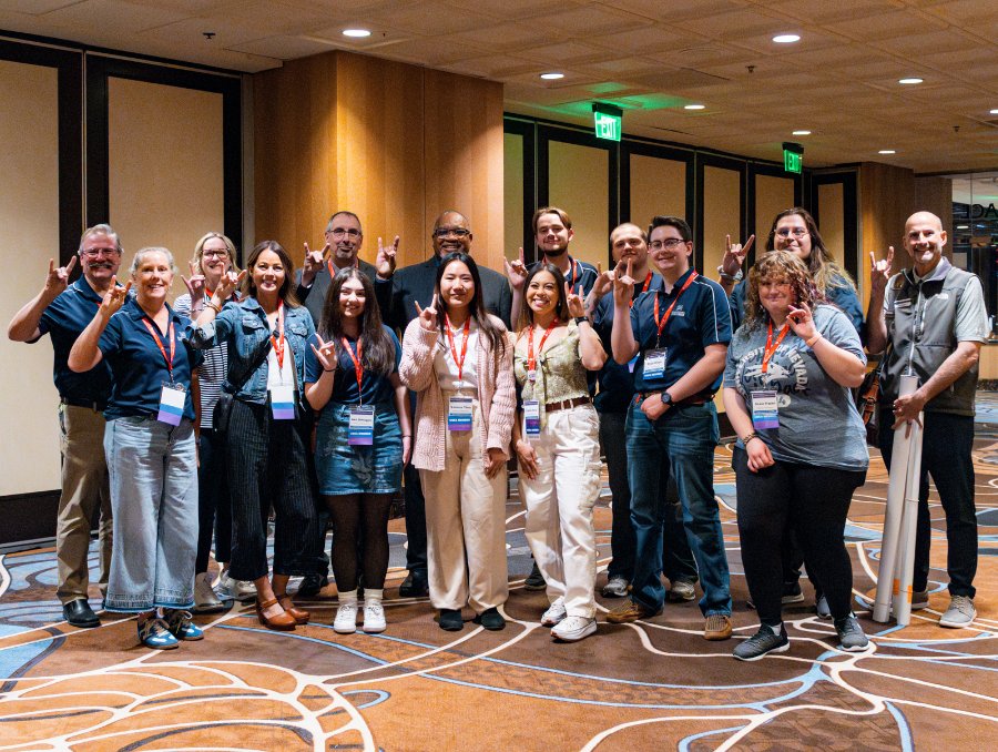 A group of 15 of the conference organizers, holding wolf pack hand signs.
