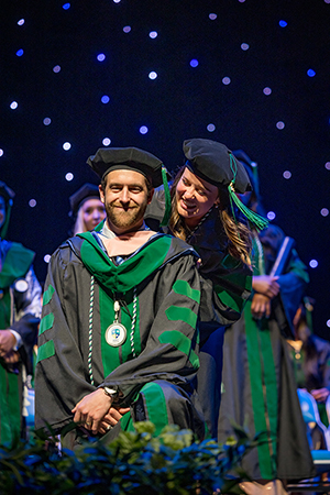 Andrew Cobourn being hooded by his wife and fellow graduate Kallie Cobourn.